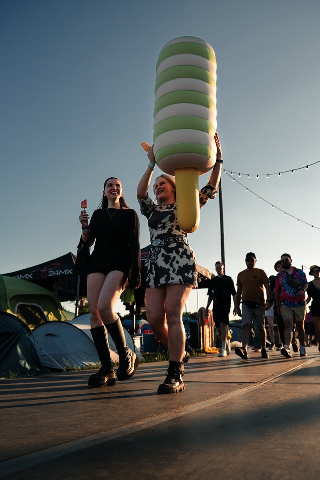 Eine junge Frau trägt die riesige aufblasbare Produktnachbildung des Twister-Eis über ein Festivalgelände.